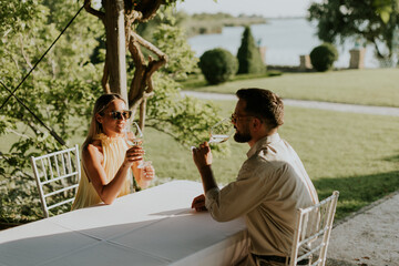 Naklejka premium Lovely couple enjoys wine together by the serene lakeside at sunset