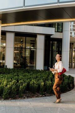 Korean woman enjoying a sunny day while walking near a modern building