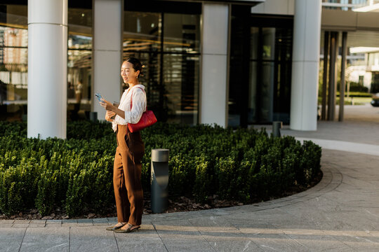 Korean woman enjoying a sunny day while checking her phone outside