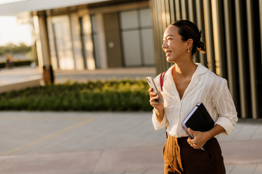 Bright afternoon stroll of a Korean woman with a smile in a modern urban setting
