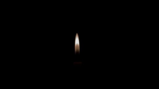 A lone candle flame flickering gently against a completely dark backdrop.