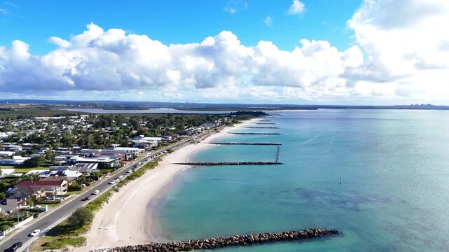 Aerial tracking along Kurnell white sand beach with breakwaters and coastal homes, drone establishing, Kurnell NSW Australia
