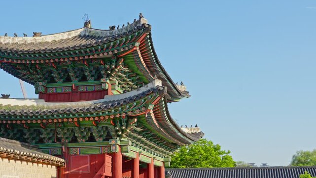 Changdeokgung Palace is a UNESCO World Heritage site featuring ornate Dancheong paintwork, curved tiled roofs, and Japsang figurines along the eaves of Donhwamun Gate under a bright sky.