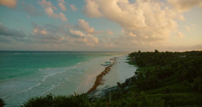 Turquoise Caribbean coast and jungle glow under warm evening clouds in Tulum Mexico