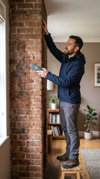 Inspector measuring damp on a brick chimney breast using a moisture meter
