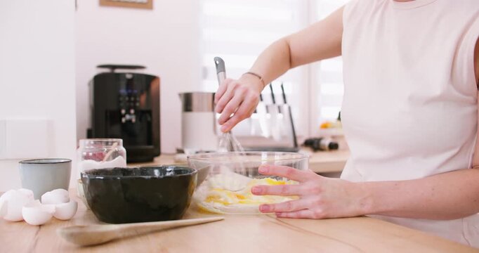 Pastry preparation. Whisking process. Female chef hand mixing sugar cream egg yellow mass for homemade dough in glass bowl on table.