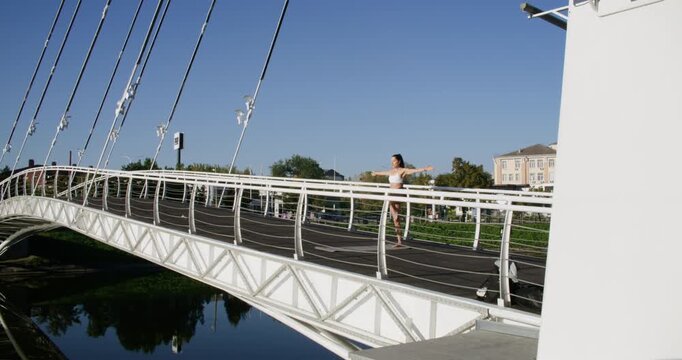 City yoga. Urban wellness. Active female training sportive body workout performing balancing pose barefoot on bridge in park.