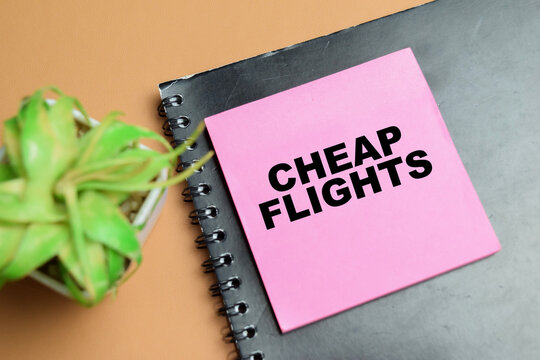 Concept of cheap flights write on sticky notes isolated on table.