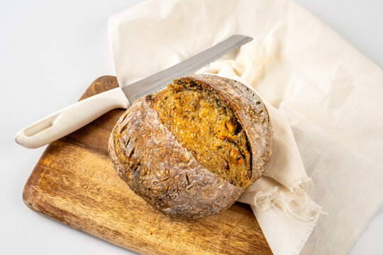 Crispy sourdough bread on a wooden board with knift and white cotton fabric and on white background.