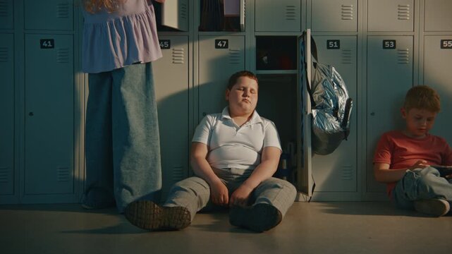 Elementary School Student Sitting Silently on Metal Lockers in School Break, Expressing Sadness and Isolation. School Life, Emotional Health, Childhood, Resilience, Supportive Learning Environment.