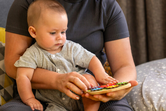 Caregiver Guiding Baby Hand On Colorful Gear Puzzle