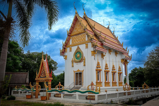 Beautiful Thai temple ordination hall under dramatic blue sky