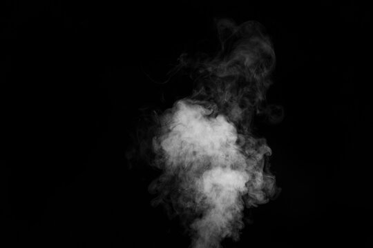 Curly white steam rising up and splashing water scattering in different directions isolated on a black background