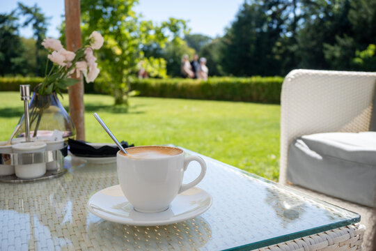 Morning coffee in the garden of a public park at a local cafe. Tranquility scene.