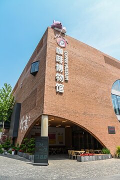 Beijing, China &mdash; April 25, 2026: Vertical view of the Coffee Museum building with modern red brick architecture and large archway in 798 Art Zone.