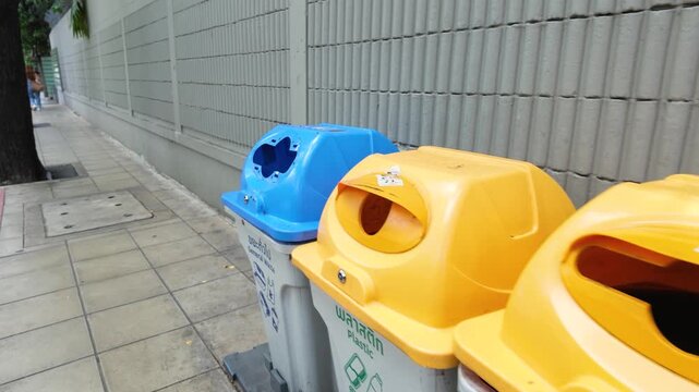 Row of Plastic Recycling and Garbage Bins on Urban Sidewalk