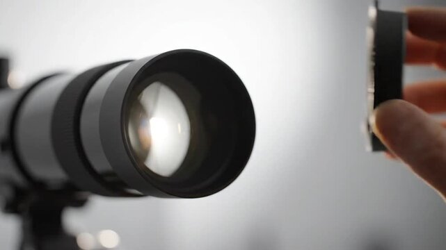 Hand removing telescope lens cap for indoor astronomical observation.