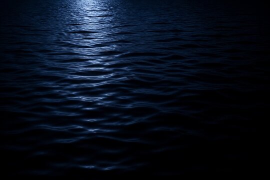 Moonlight reflecting on dark ocean water surface at night