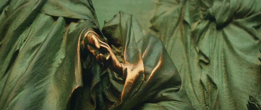 Shiny bronze hands on Milan Cathedral statue reflect years of tourist interaction in Italy