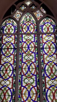 4K footage of colorful stained glass church window with memorial plaques on old wall, showcasing Christian architecture, sacred heritage, religious art and peaceful worship atmosphere.