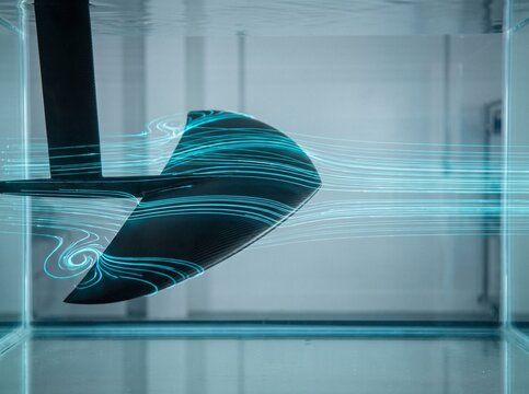 Submerged carbon fiber hydrofoil wing in testing tank with glowing cyan laser flow lines illustrating hydrodynamic laminar flow