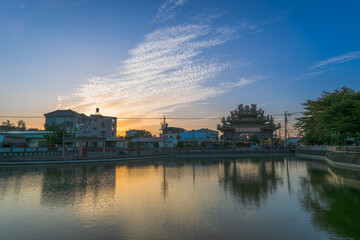 Fototapeta premium Scenic view of a traditional Taiwanese temple and buildings reflected in a calm pond during sunset in Tainan, Taiwan.