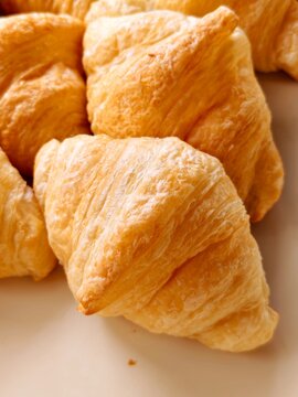 Close-up view of freshly baked golden-brown butter croissants showing detailed flaky texture. Perfect for bakery menu, breakfast background, cafe advertisement, and food photography.