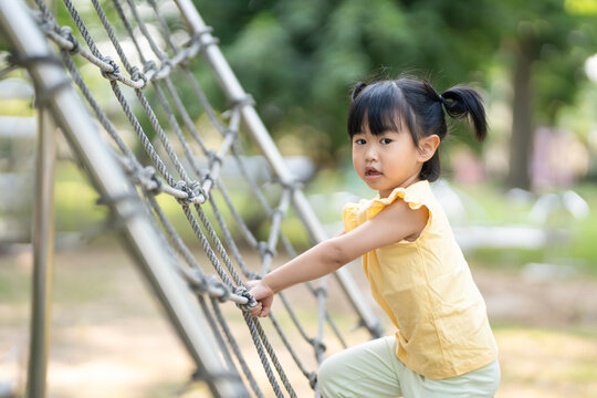 child climbs up an alpine grid in a park on a playground on summer day. children playground in a public park, entertainment and recreation for children, holiday, IQ, EQ, Relax, Development