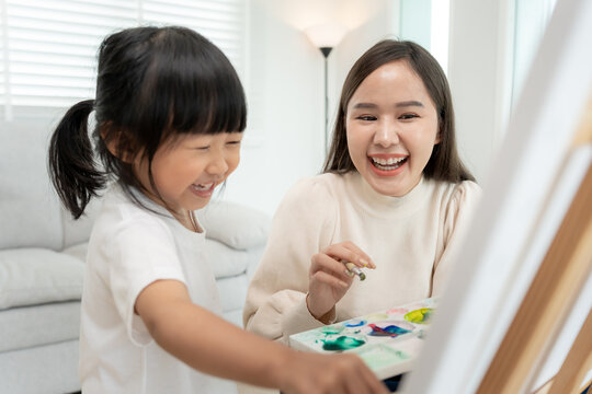 Happy Asia mother playing learning paint for little girl. Funny family is happy and excited in the house. Mother and daughter  having fun spending time together. Holiday, Activi