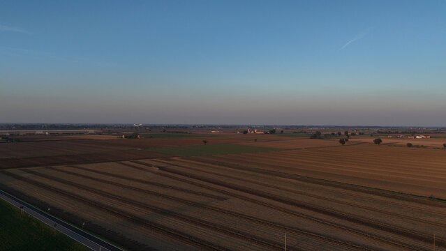 Po Valley farmlands extending across Emilia Romagna, Italy, highlighting diverse crop cultivation and agricultural activity under a clear sky at dusk