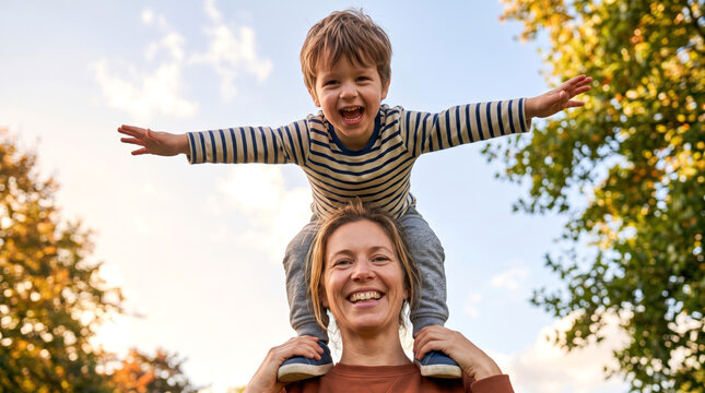 Mother Carrying Son on Shoulders Pretending to Fly Outdoors