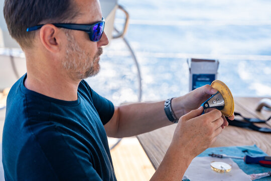 Man repairing yacht equipment with hand tools during a sailing trip on the Adriatic Sea. Concept of boat maintenance, DIY repair, seamanship, technical skills and self-sufficient sailing.