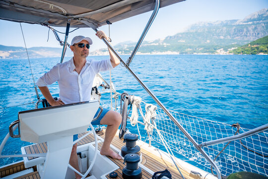 Man steering a sailing yacht on the Adriatic Sea near the Bay of Kotor in Montenegro. Freedom, sailing lifestyle and adventure travel on a private yacht.