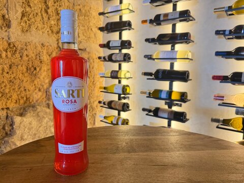 Palma, spain, august 2, 2026, sarti rosa aperitivo bottle standing on wooden table in a traditional italian wine cellar or bar