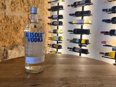 Palma, spain, august 2, 2026, absolut vodka bottle on rustic wood table in wine cellar, displaying premium spirit in traditional setting