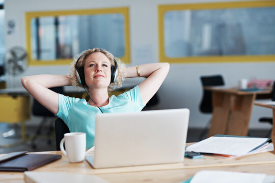 Woman, headphones and relax in office with laptop, finished project or self affirmation podcast. Editor, smile or music in agency with tech, productivity or completed article with submission deadline