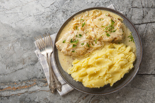 German Zwiebel schnitzel pork cutlets with a rich onion cream sauce with mashed potatoes closeup on the plate on the table. Horizontal top view from above
