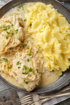 Fried Zwiebel Schnitzel simmered with onion cream sauce and served with mashed potatoes close-up in a plate on the table. Vertical top view from above