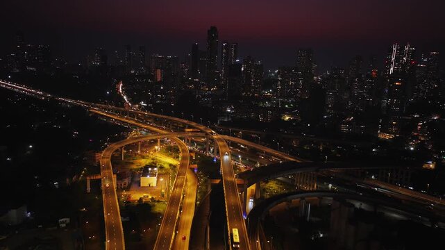 Drone hyperlapse aerial shot of Atal Setu in Mumbai at night, showcasing the dynamic cityscape illuminated with vibrant lights. The footage captures the fast-paced movement of traffic and clouds.