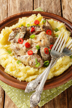 Fried chicken liver with cream sauce with mashed potatoes closeup on thr plate on the wooden table. Vertical