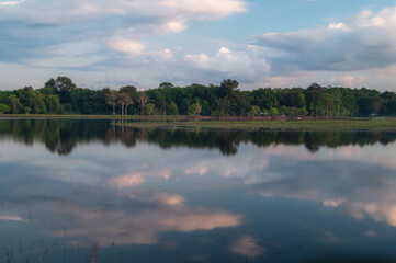 Obraz premium A pond with reflections of the clouds in the sky, with mountains in the background, in the evening.
