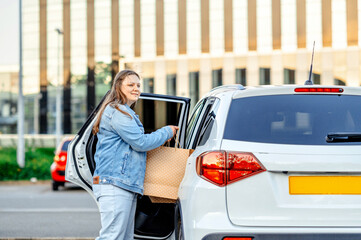 Smiling woman loading shopping bag into car