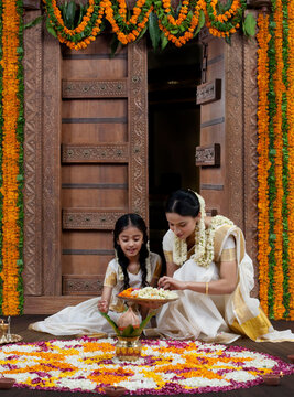 South Indian woman helping her daughter with a rangoli 