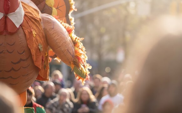 Thanksgiving Day Parade giant turkey float with a crowd of spectators watching the festive autumn holiday celebration outdoors