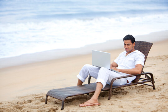 Man with a laptop at a beach 