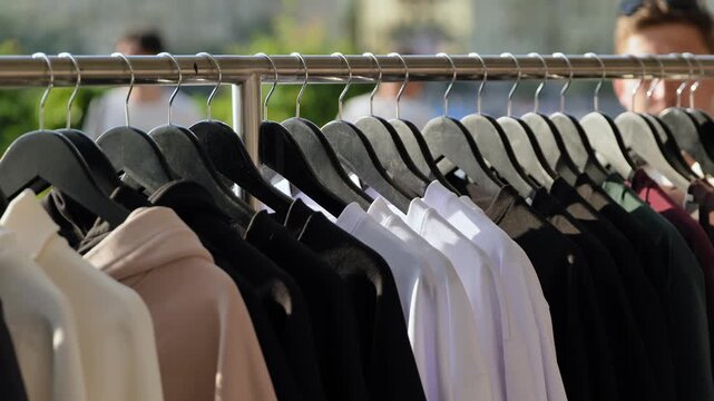 Clothing rack displaying hanging hoodies and shirts in various colors for sale
