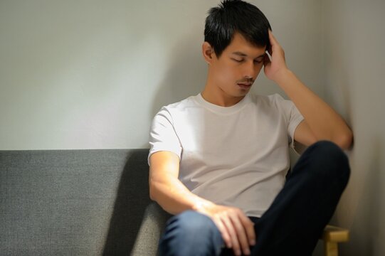 Young Man Sitting in a Gray Couch with Contemplative Expression