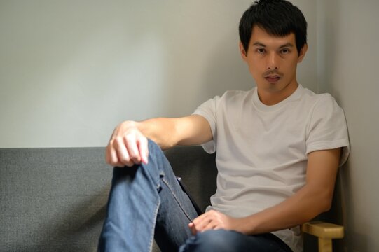 Young Man Relaxing on Couch in Casual Outfit with Soft Lighting