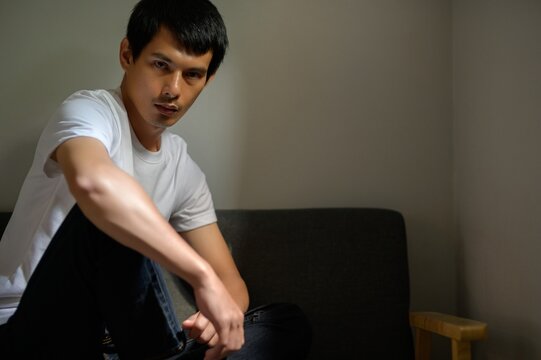 Thoughtful Young Man Posing in Minimalist Room with Natural Light