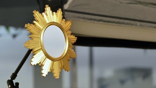 Golden sunburst mirror reflecting room details and studio equipment